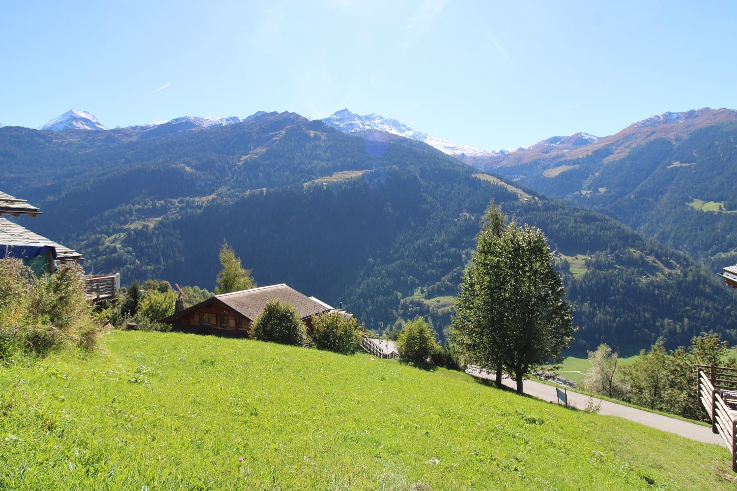 Le pré et, au-delà des chalets, la chaîne de sommets enneigés qui ferme la vallée.